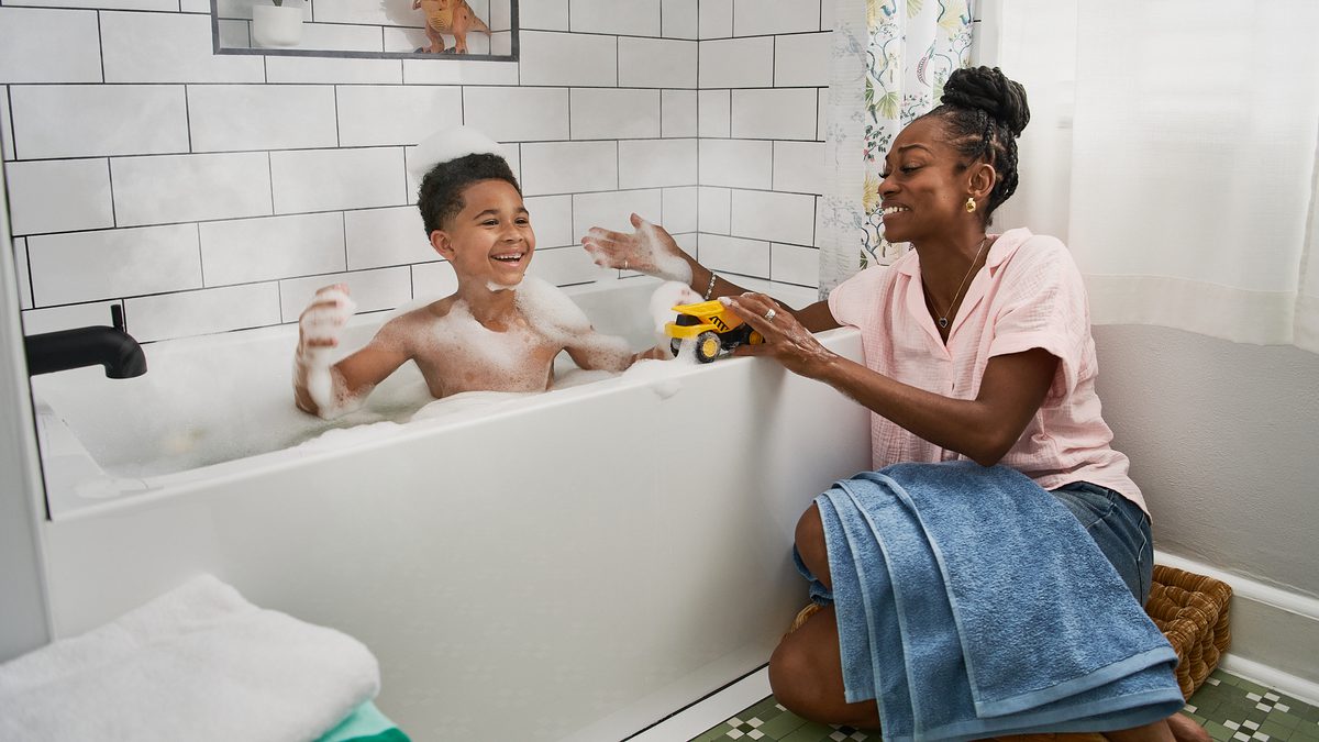 Mother and child enjoying warm bath run by natural gas in a bright family bathroom.