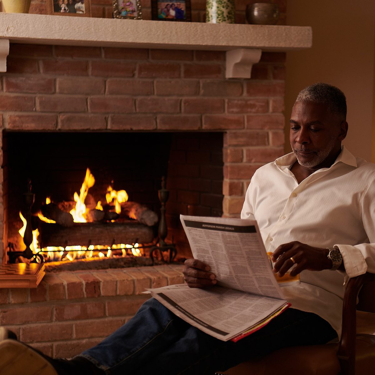 Man reading by the glow of a natural gas fireplace in a comfortable living space.