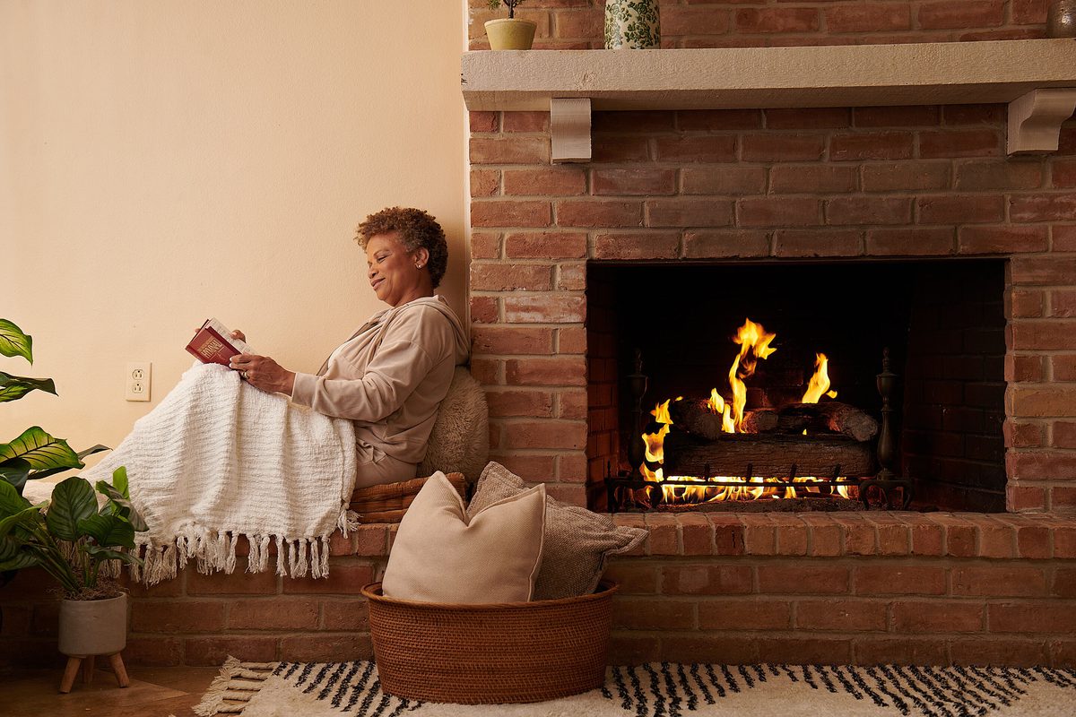 Woman sitting near a warm natural gas fireplace at home