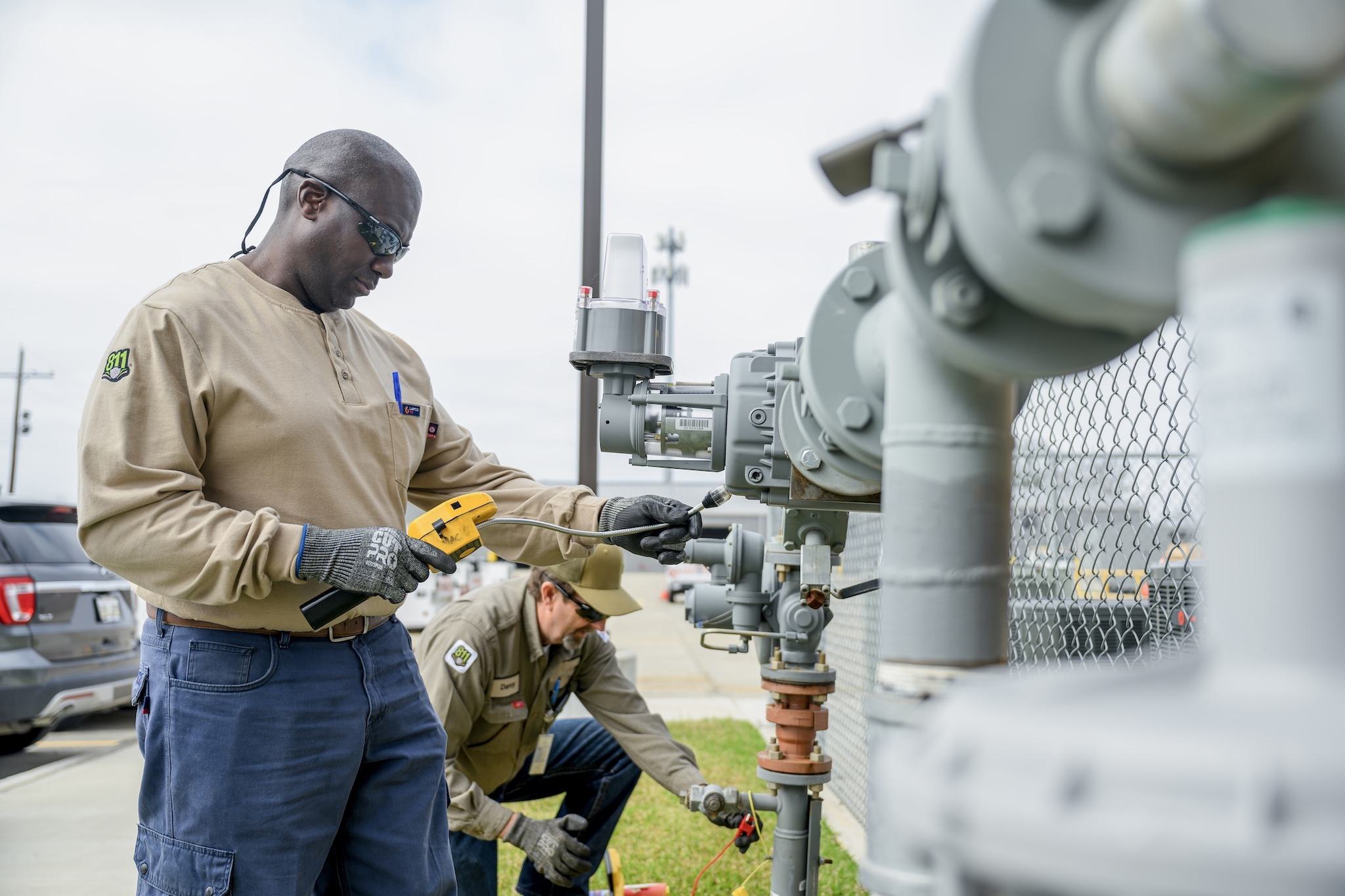 Two Delta Utilities Workers Repairing A Gas Meter Two delta utilities workers repairing a gas meter