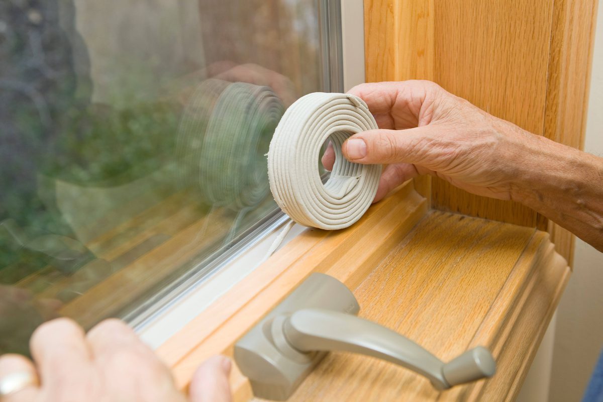 Person putting a weather strip on the bottom of a window